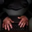 A laptop user with their hood up