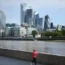 A jogger runs along the Thames Path against a backdrop of the City of London