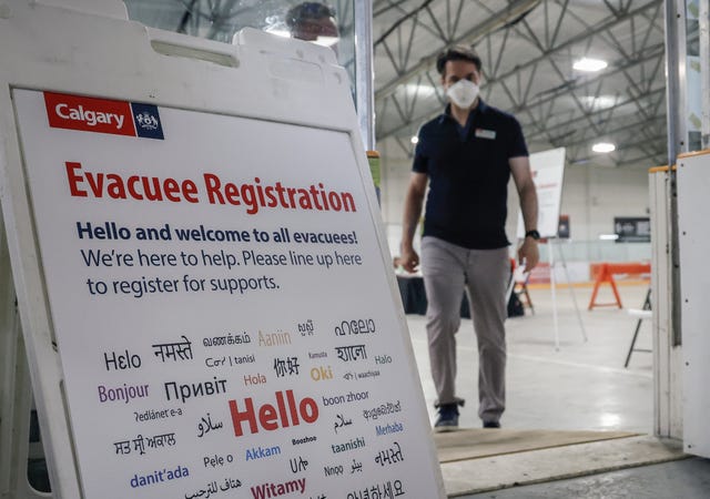 ac2ae3b21c694a17800fdd03a9f8b91c A man in a mask approaches an Evacuee Registration sign