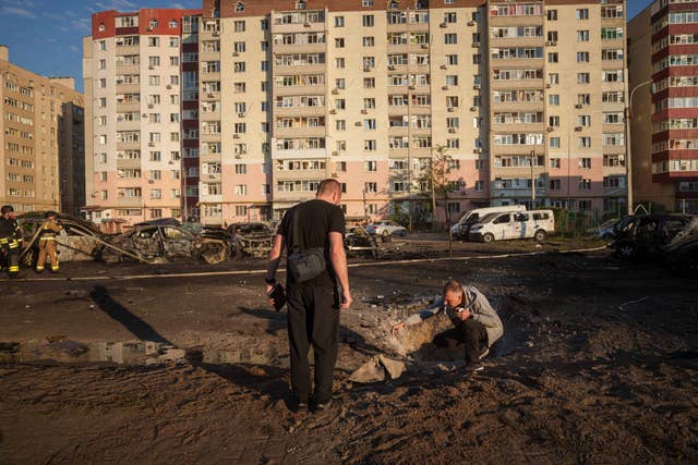 5fc40ff9b98e4300a8afff120844b828 Young men look at shrapnel after a Russian air strike on a residential neighbourhood in Sumy, Ukraine
