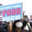 Woman in a face mask holds a sign that says "President Tinubu, let the poor breathe"