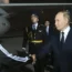 Putin shaking hands with a man in a tracksuit top and blue cap