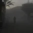 A Palestinian walks on a smoke-filled street after an Israeli air strike in Deir al Balah in the Gaza Strip