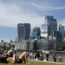 People sit on the grass overlooking the City of London