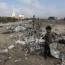 A Palestinian child stands next to piles of garbage thrown between the tents of displaced people in Deir al-Balah in the central Gaza Strip