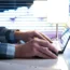 Man using laptop in modern business office with blurred city