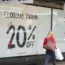 A shopper passes closing-down sale signs in a shop