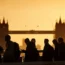 The silhouette of commuters walking across a bridge, with Tower Bridge in the background