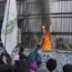 A man is seen throwing a water bottle as protesters stand next to a fence, some holding flags, while others try to scale the fencing