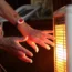 A pensioner warms her hands by an electric heater