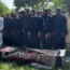 A line of men by a coffin draped in a cloth