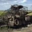 A destroyed Russian tank sits on a roadside near the town of Sudzha in the Kursk region