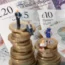 Models of people on piles of coins and banknotes