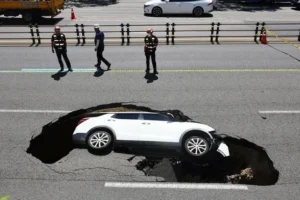 Elderly woman suffers cardiac arrest as couple’s car plunges sideways into sinkhole