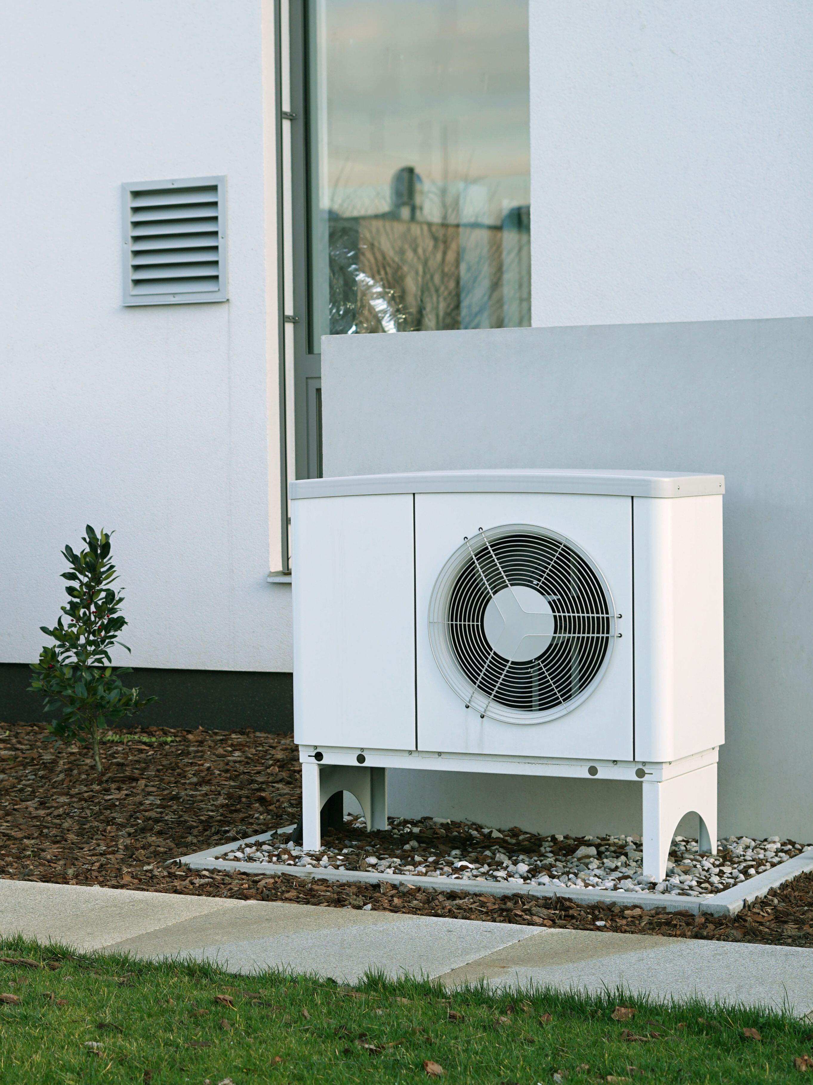 fd6a23bf-ef15-471e-b253-507a7d4f76aa A white heat pump standing against the wall of a house
